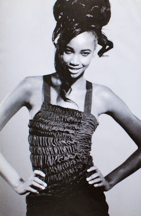 Comme des Garçons 1989 black smocked ruched suspender dress: vintage editorial photograph of model Beverly Peele wearing the bib dress with hands on hips, showing fit and scale of architectural smocking design, circa 1989