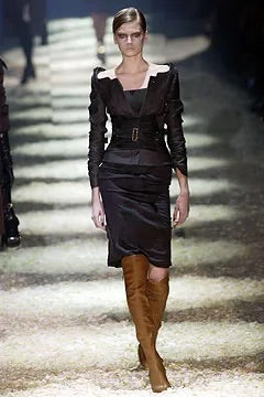 Tom Ford for Gucci FW03 black silk corset skirt on runway: model wearing skirt with structured black jacket and brown knee-high boots, Gucci Fall Winter 2003 runway show