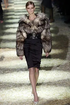 Tom Ford for Gucci FW03 black silk corset skirt on runway: model wearing skirt styled with oversized brown fur coat, pencil silhouette visible below, Gucci Fall Winter 2003 show