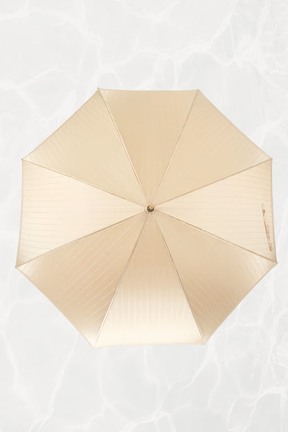 Vintage YSL Yves Saint Laurent gold umbrella: close-up of the embossed YSL monogram on the gold handle showing the crisp lettering and luxe finish