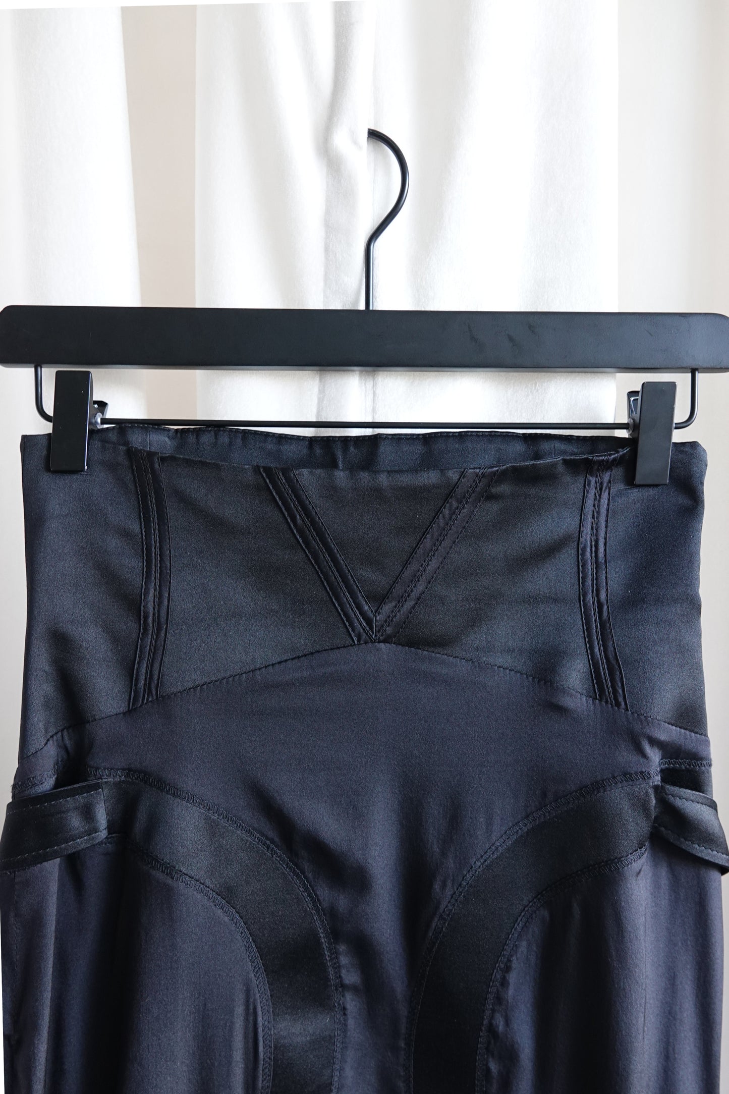 Tom Ford for Gucci FW03 black silk skirt waistband close-up: v-notch corset waist with curved seam panel boning channels, side strap hardware visible both sides, Fall 2003