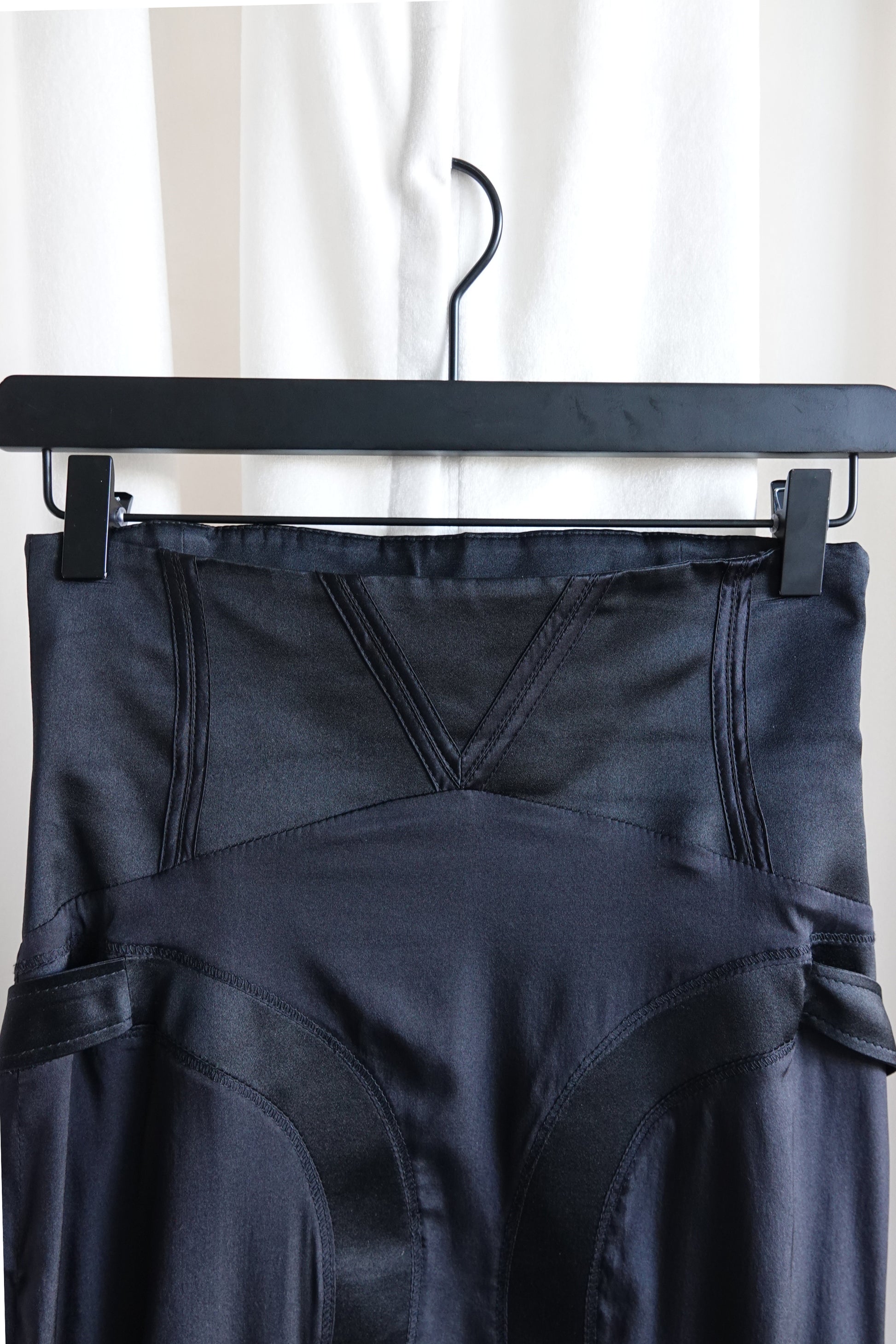Tom Ford for Gucci FW03 black silk skirt waistband close-up: v-notch corset waist with curved seam panel boning channels, side strap hardware visible both sides, Fall 2003
