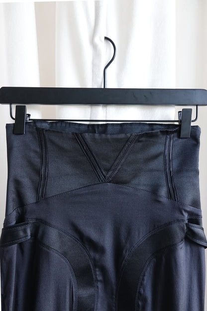 Tom Ford for Gucci FW03 black silk skirt waistband close-up: v-notch corset waist with curved seam panel boning channels, side strap hardware visible both sides, Fall 2003