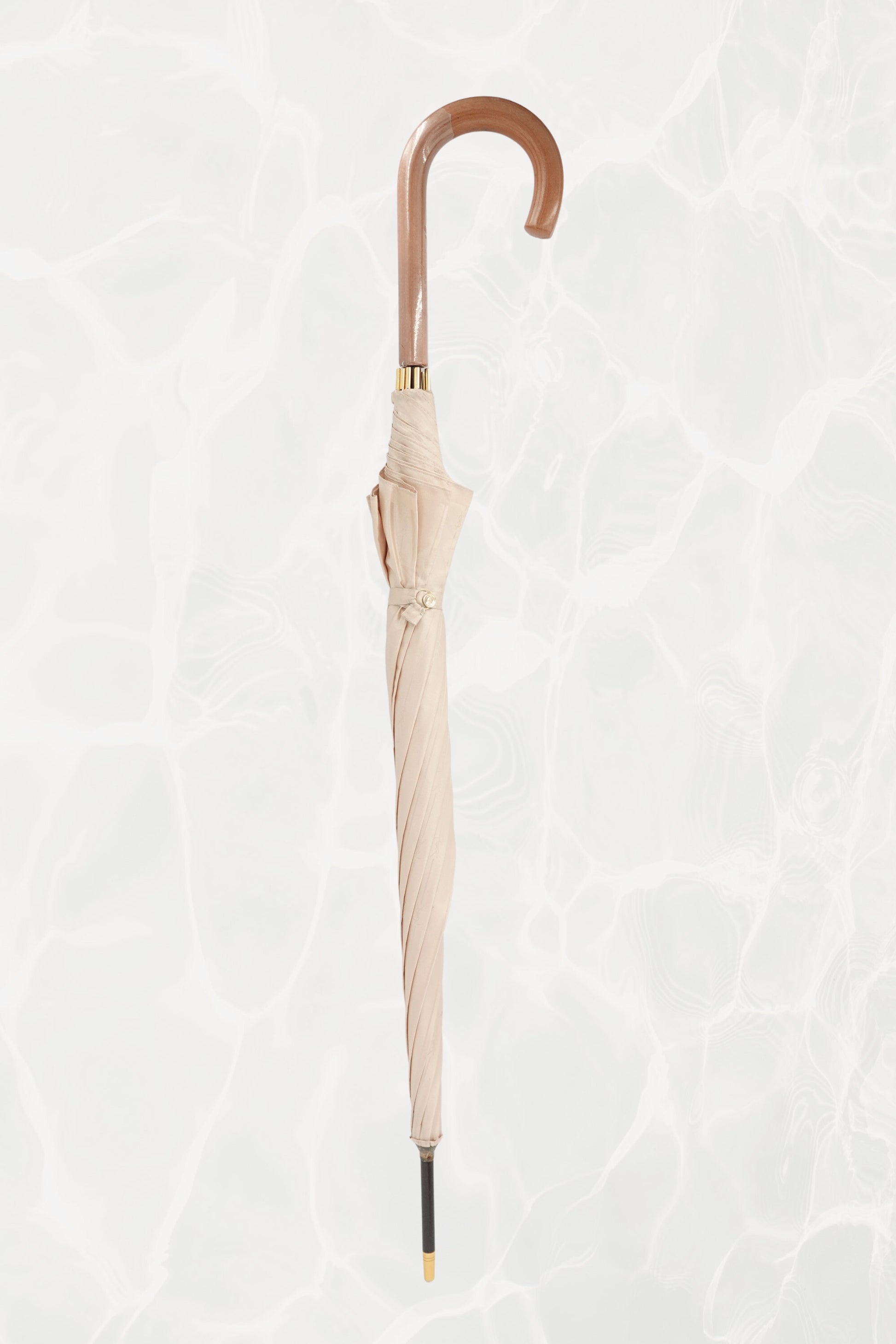 Vintage YSL Yves Saint Laurent gold umbrella: angled view of the handle showing the embossed YSL monogram from a different perspective against the canopy