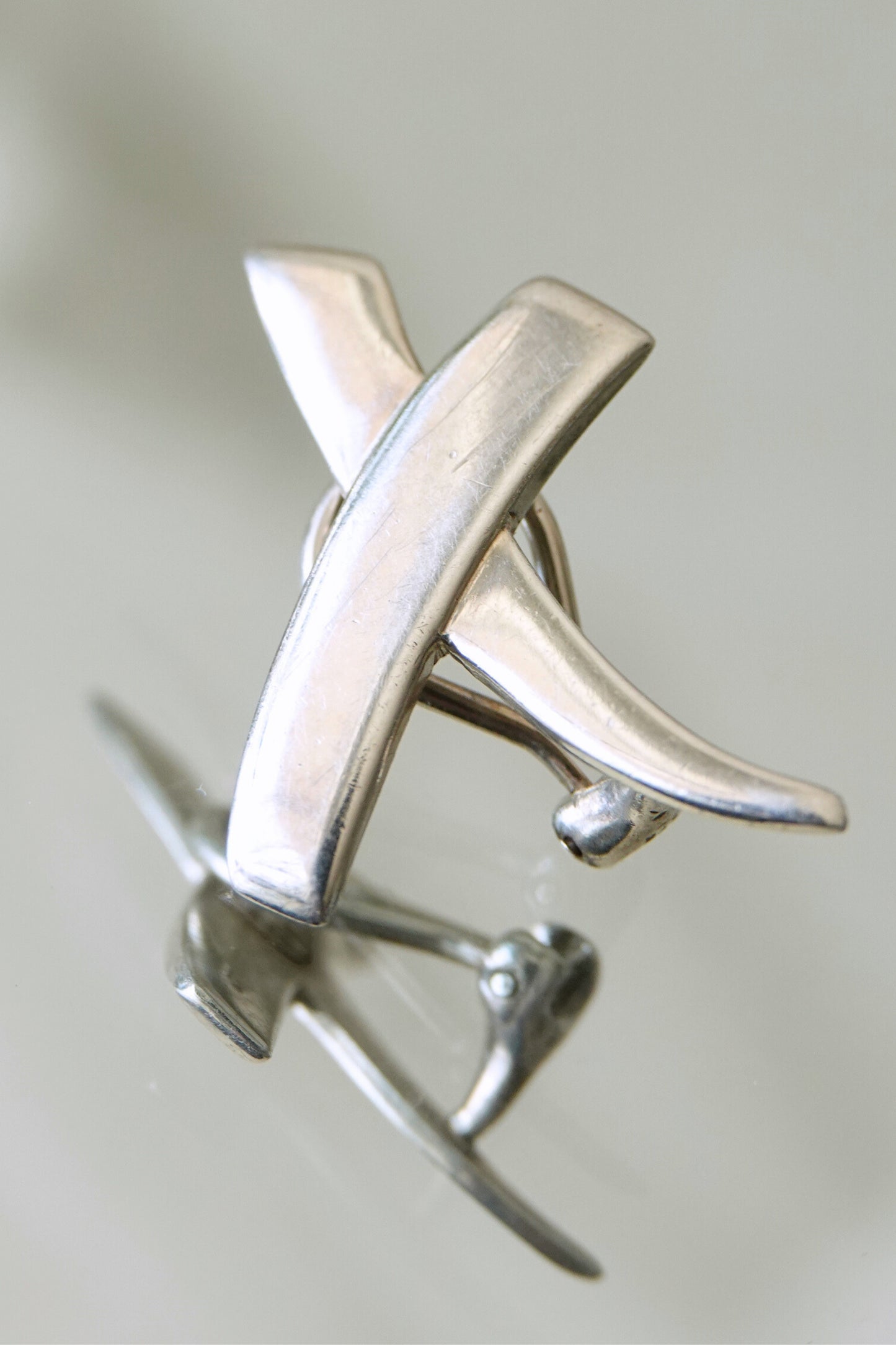 Vintage 1985 Paloma Picasso for Tiffany & Co. sterling silver Kiss X earrings: overhead flat lay of the pair showing matching X motifs and post backs on neutral surface