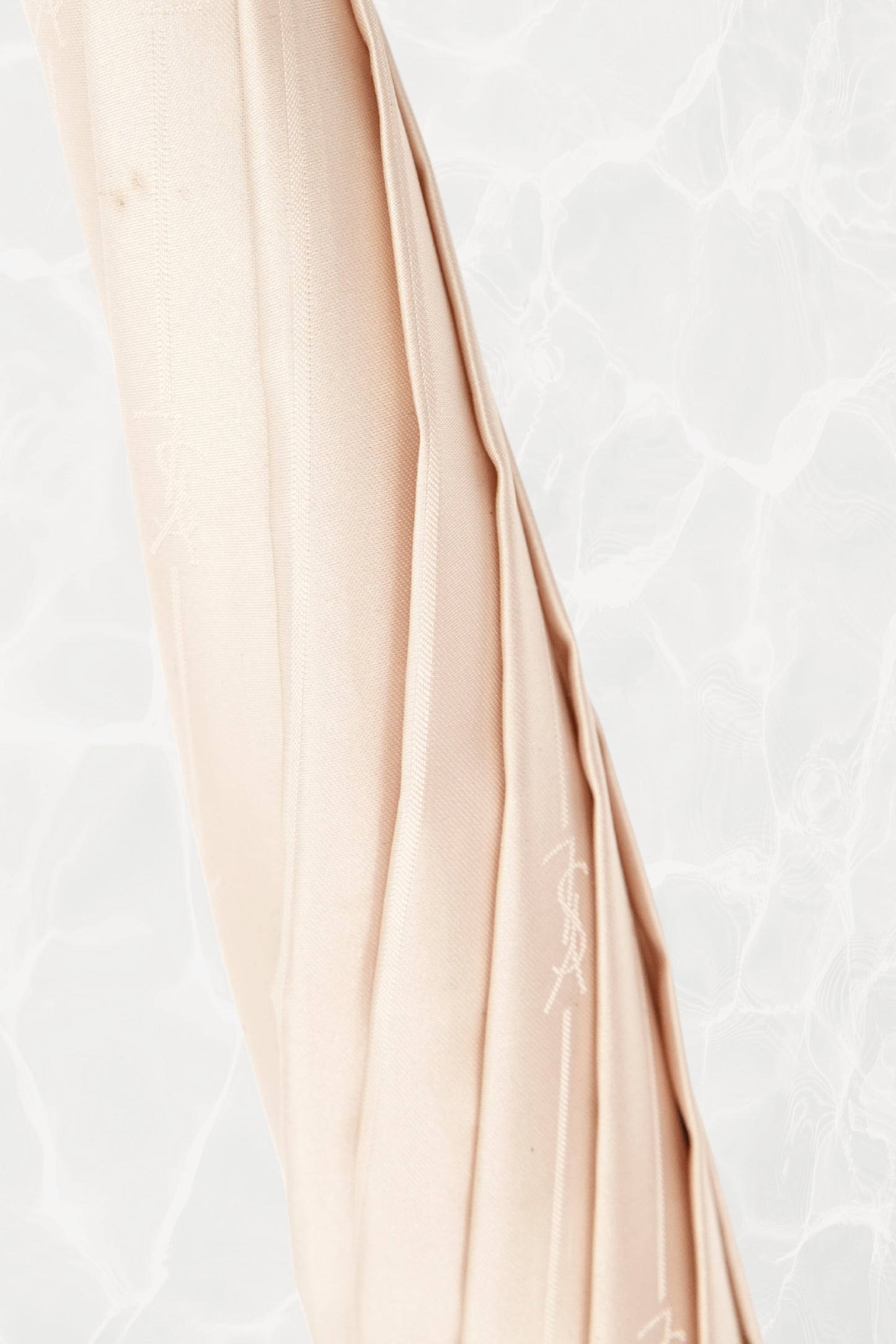 Vintage YSL Yves Saint Laurent gold umbrella: handle detail showing the curved hook shape and polished gold finish with the embossed monogram