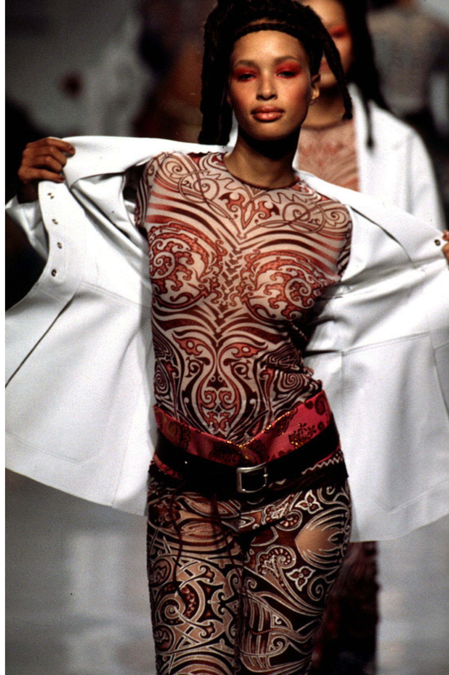 Jean Paul Gaultier SS96 runway archive: model wearing Cyberbaba tribal print top and pants with red satin belt, Spring/Summer 1996 catwalk show