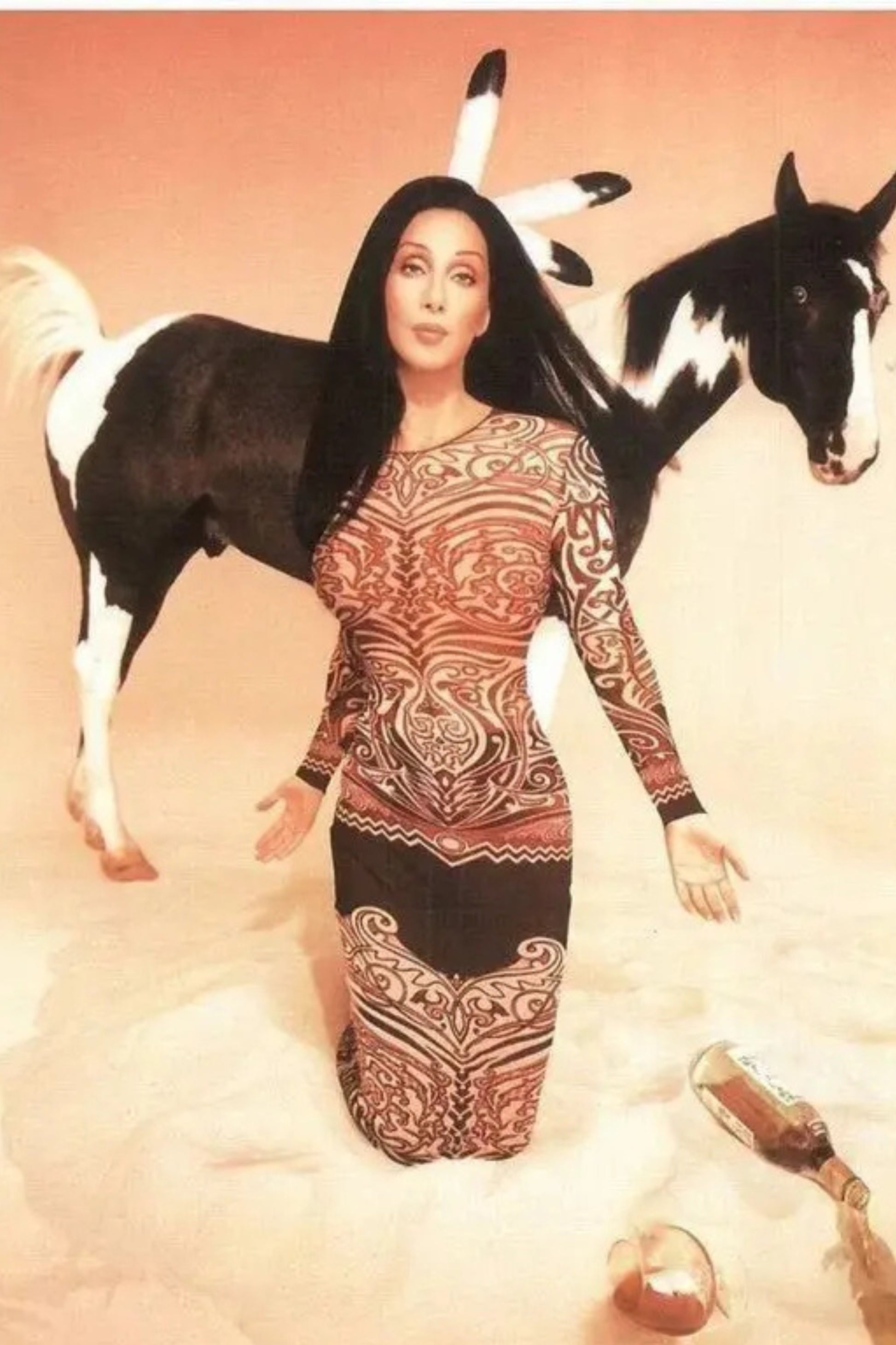 Jean Paul Gaultier JPG Jeans campaign archive: model in Cyberbaba tribal tattoo print jersey bodycon dress kneeling in sand with painted pony, SS96 editorial