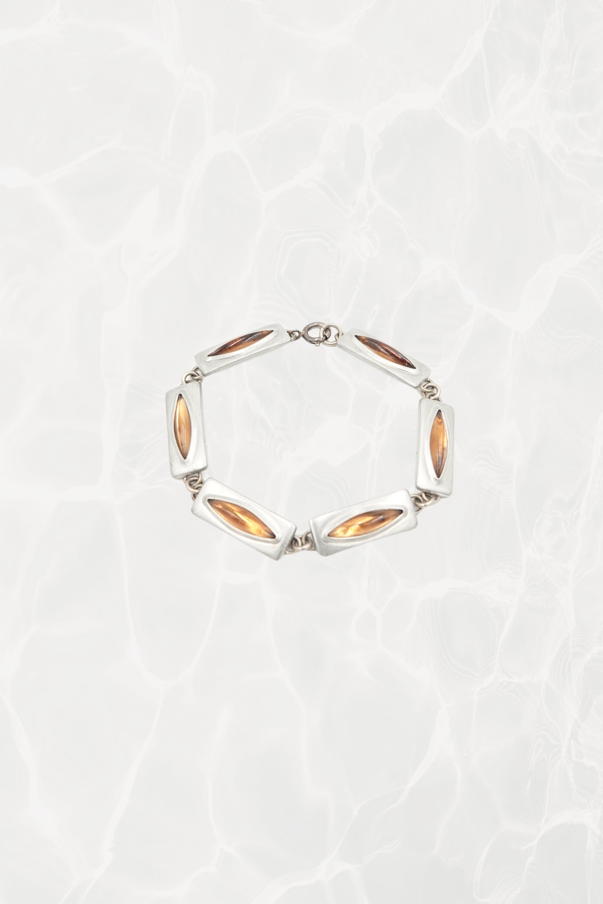 Jørgen Jensen pewter and amber glass link bracelet, Denmark — full piece coiled, pool background