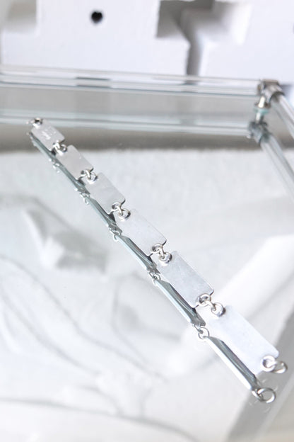 Jørgen Jensen pewter bracelet — styled on reflective glass surface, overhead view