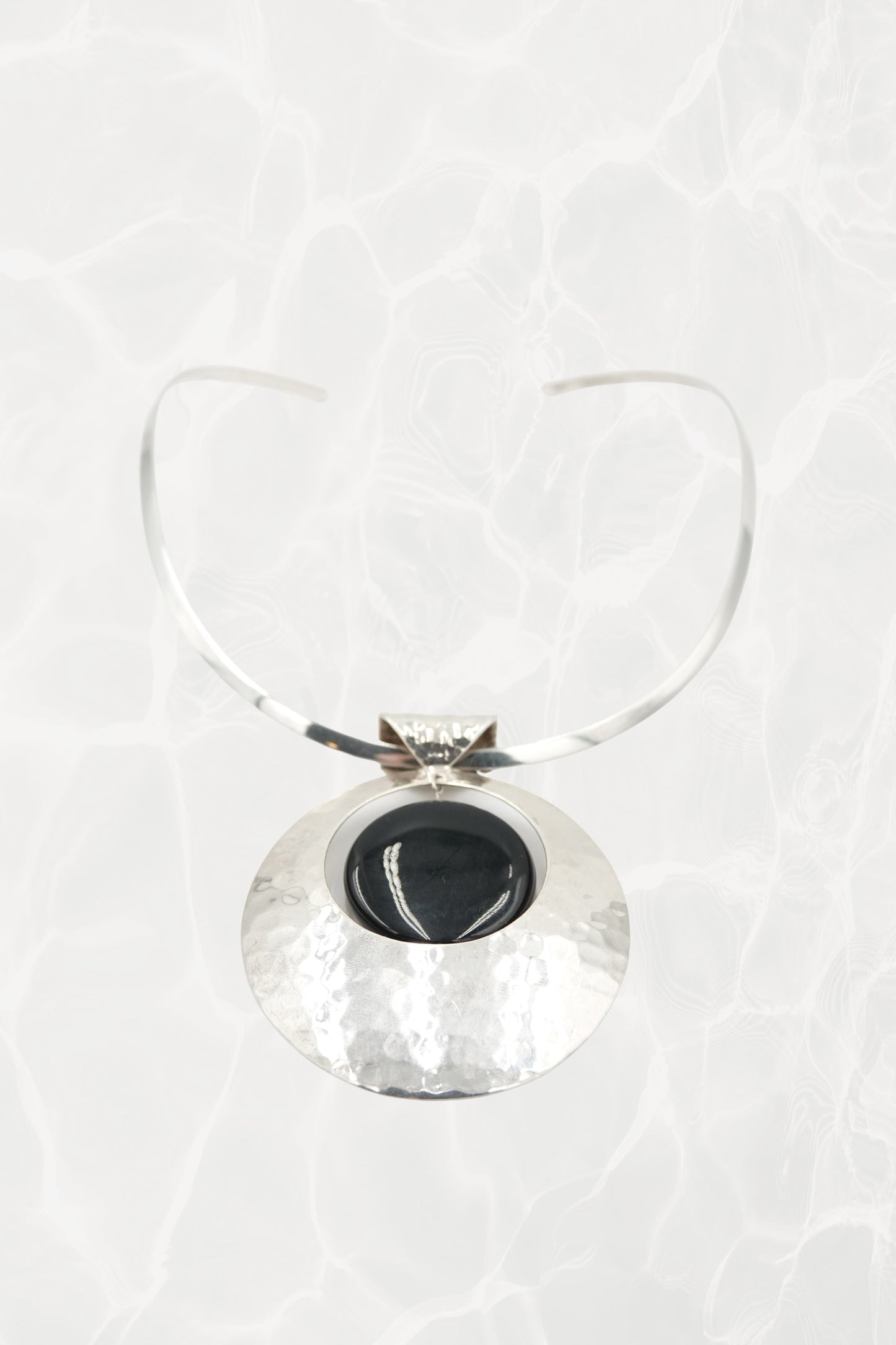 Hammered sterling silver disc pendant with neck cuff, flat lay