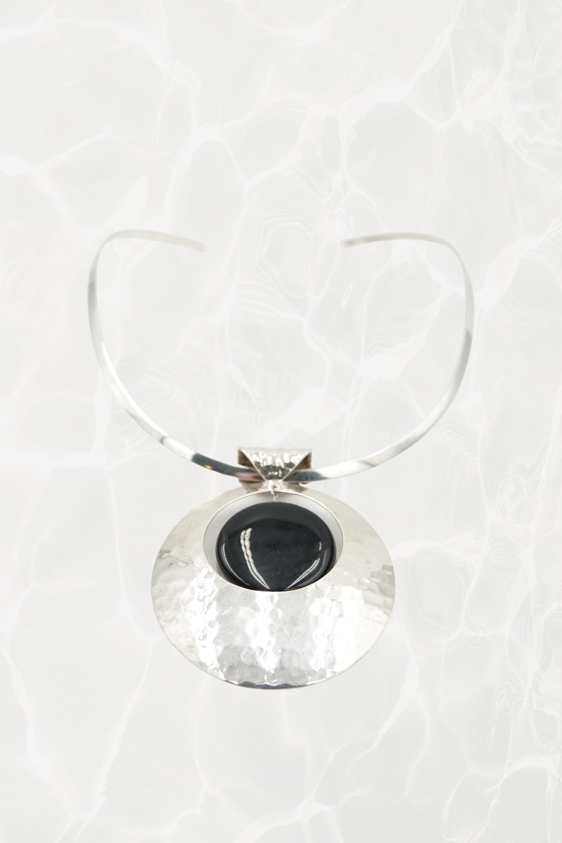 Hammered sterling silver disc pendant with neck cuff, flat lay