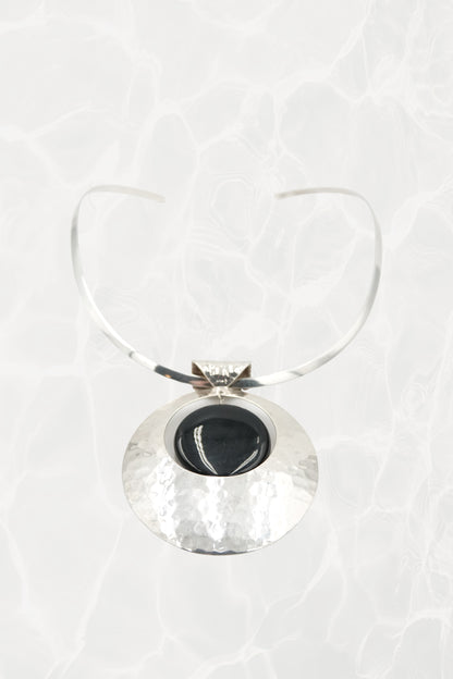 Hammered sterling silver disc pendant with neck cuff, flat lay