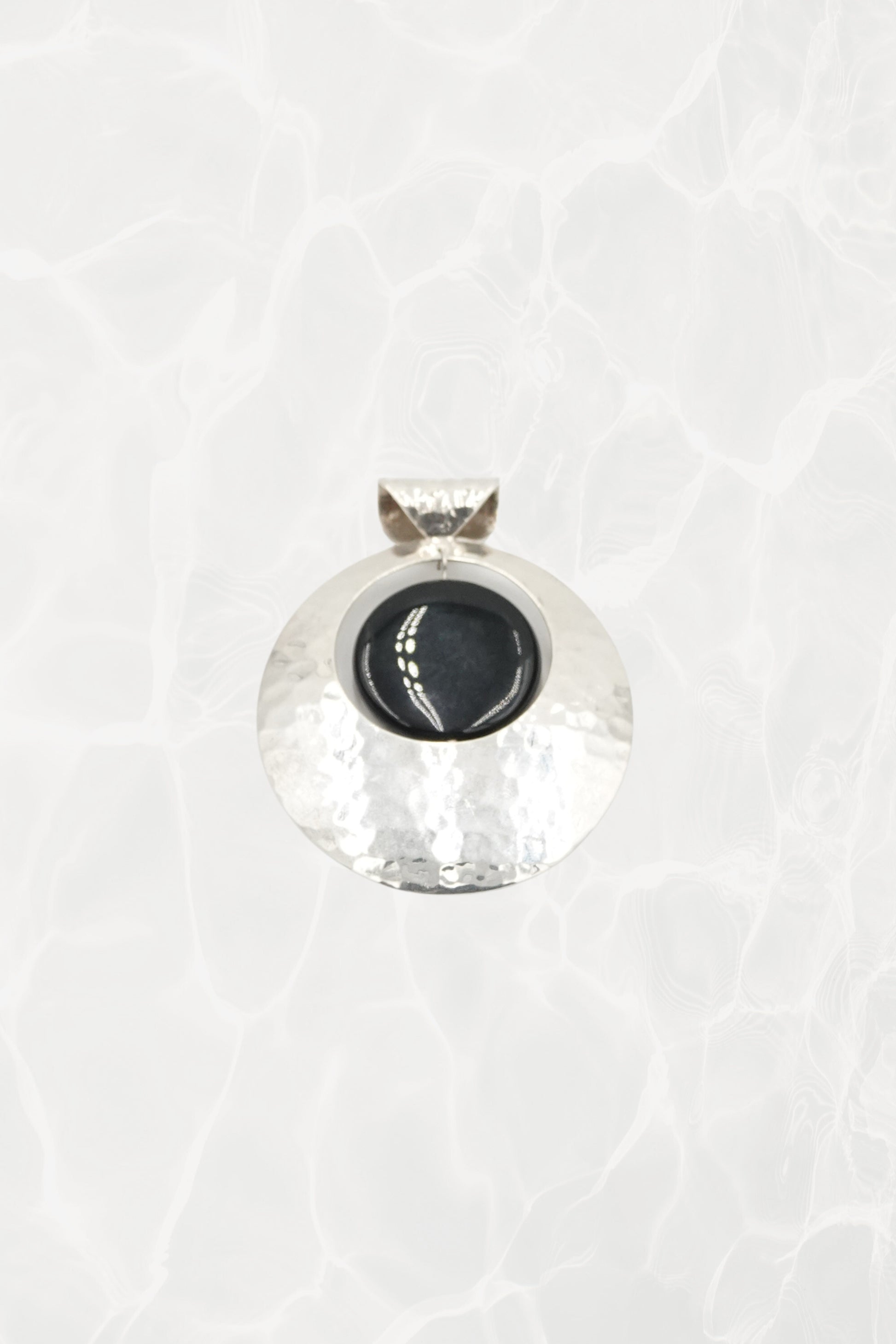 Hammered sterling silver disc pendant with black onyx cabochon, white background