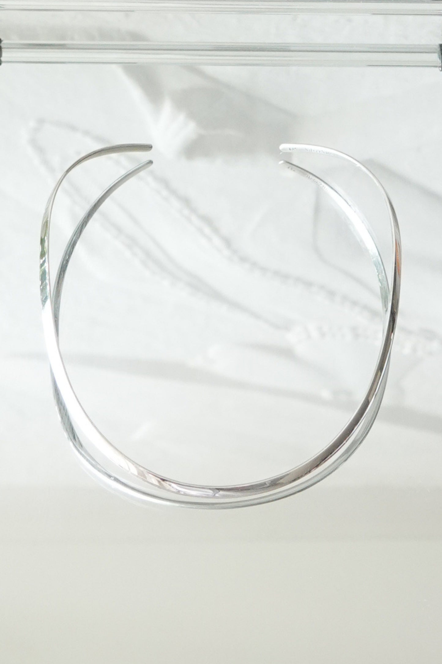 SilverSue sterling silver neck cuff styled on glass surface