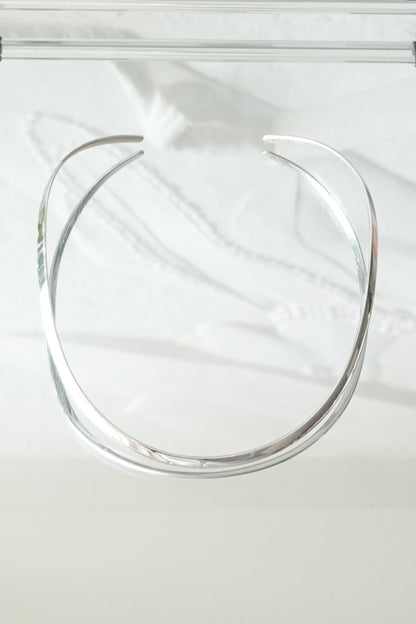 SilverSue sterling silver neck cuff styled on glass surface