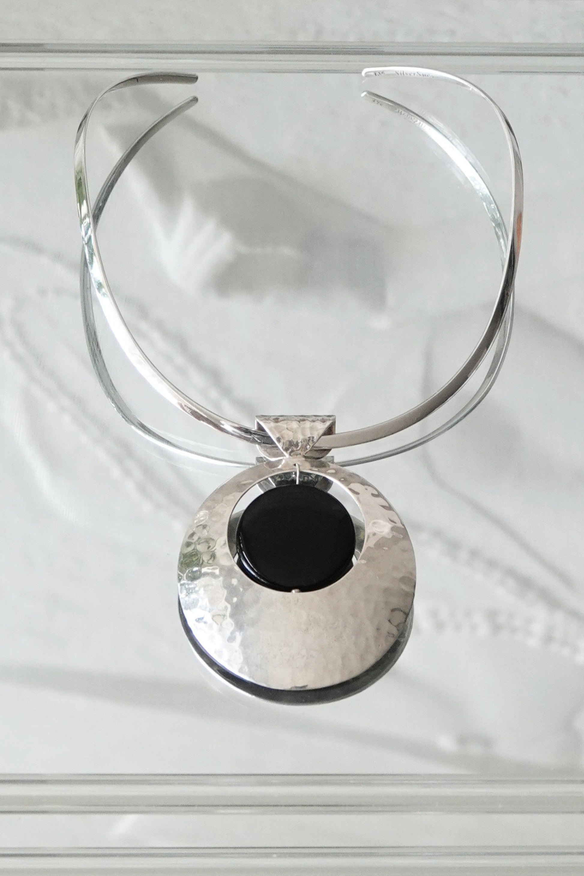 SilverSue neck cuff and pendant styled together on glass