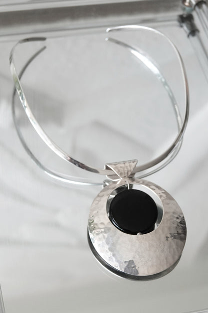 SilverSue neck cuff and pendant styled on glass, overhead angle