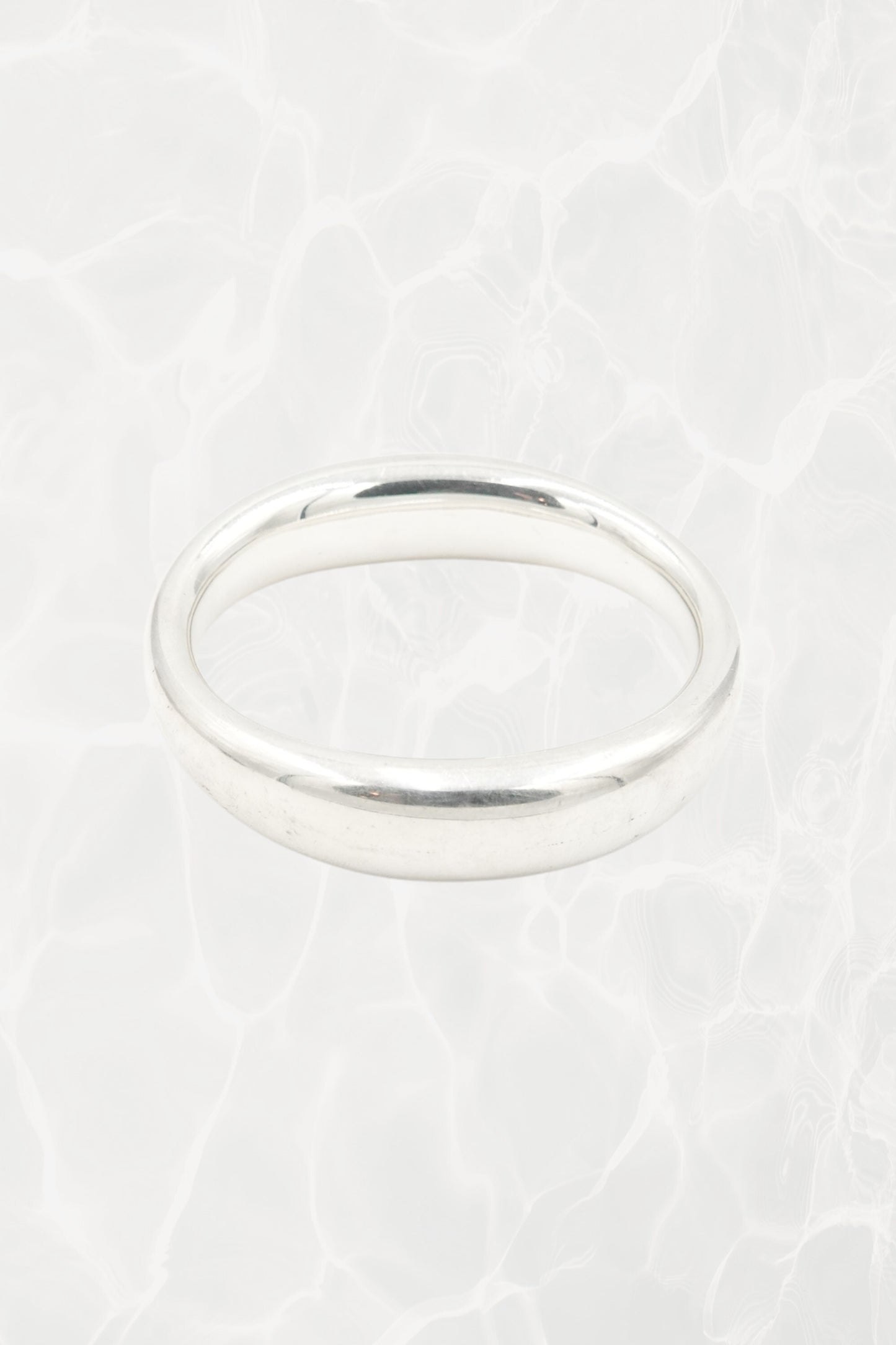 Elsa Peretti for Tiffany & Co. sculptural sterling silver closed bangle overhead view: top-down perspective of smooth oval closed form showing even width and polish of sterling silver