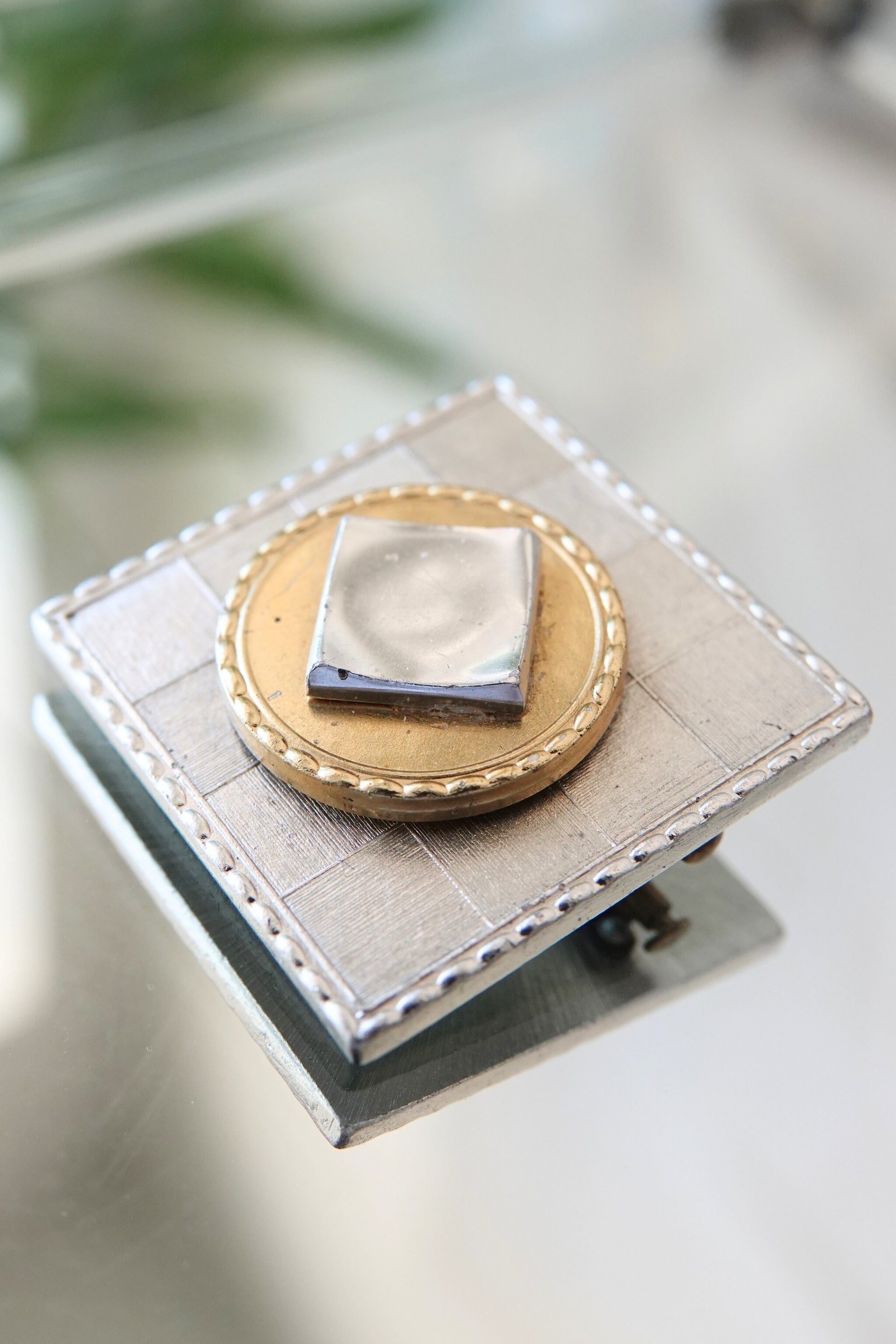 Vintage square brooch Paris — front on glass surface