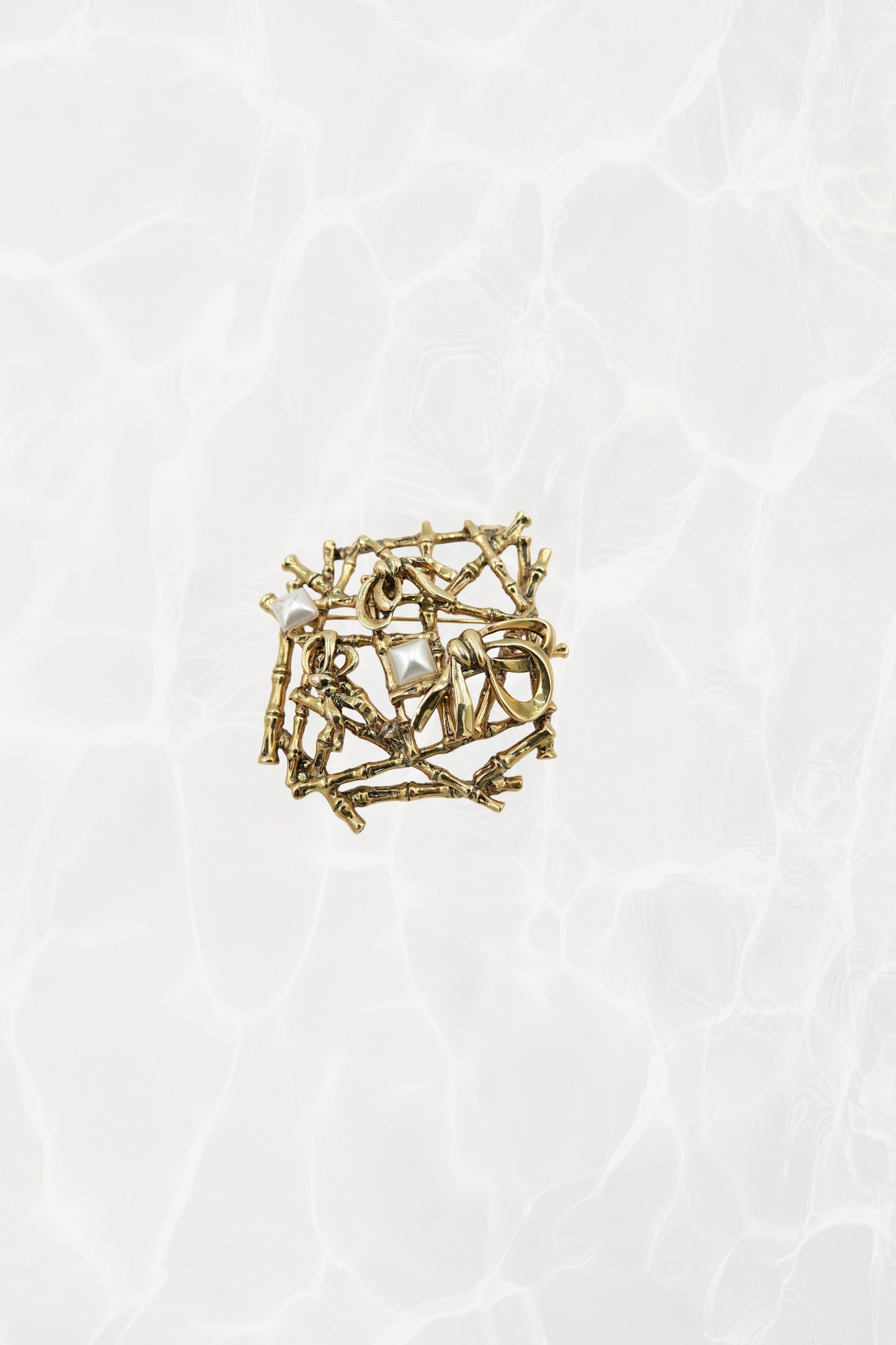 Gold-tone bamboo lattice brooch — hero front view on pool background