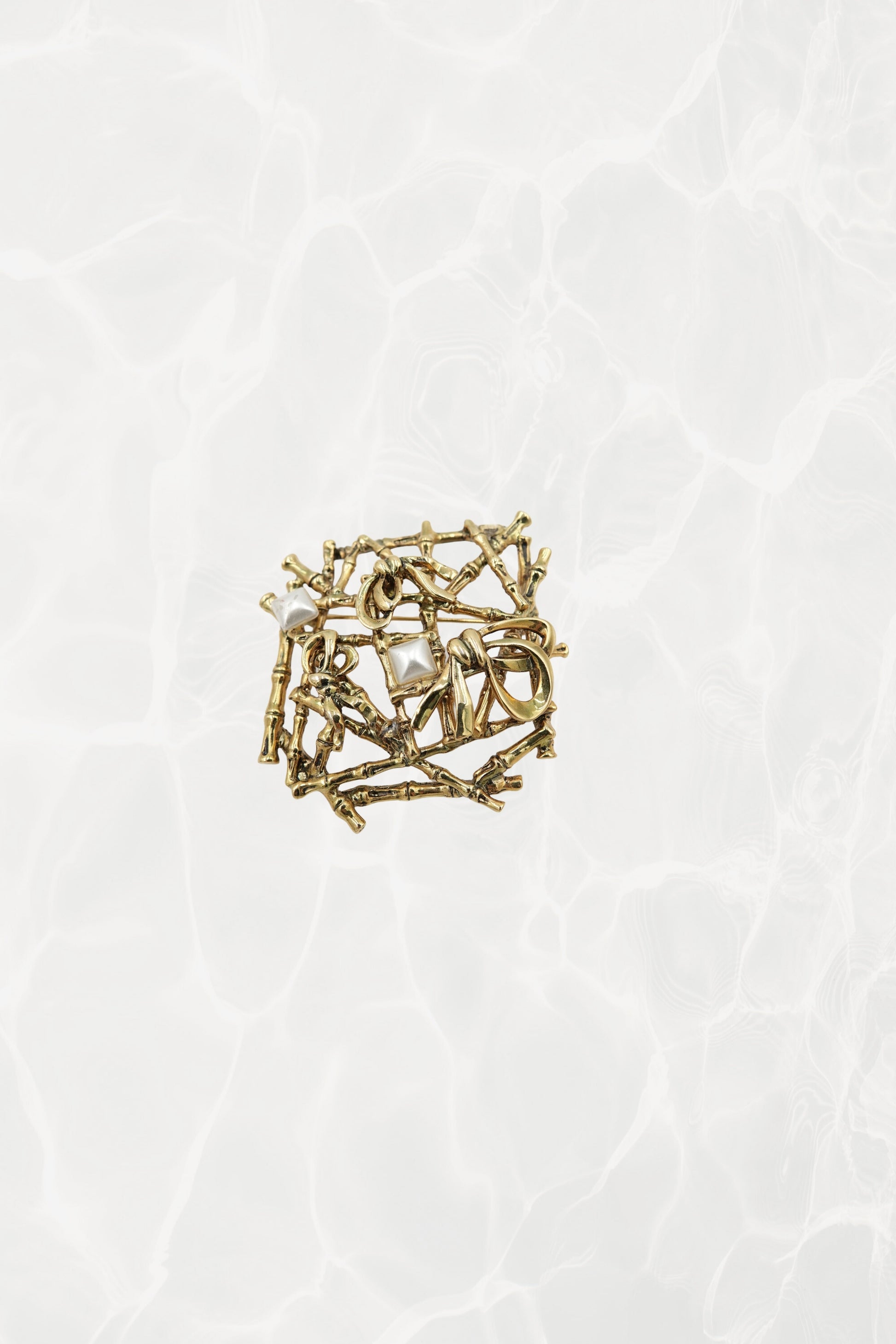 Gold-tone bamboo lattice brooch — hero front view on pool background