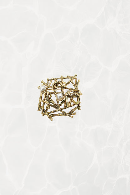 Gold-tone bamboo lattice brooch — hero front view on pool background