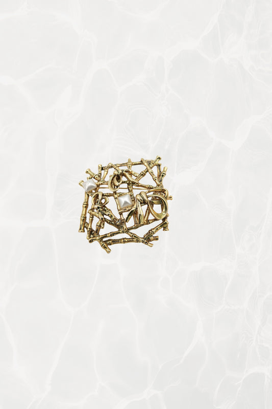 Gold-tone bamboo lattice brooch — hero front view on pool background