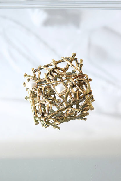 Gold-tone bamboo lattice brooch — front on glass surface