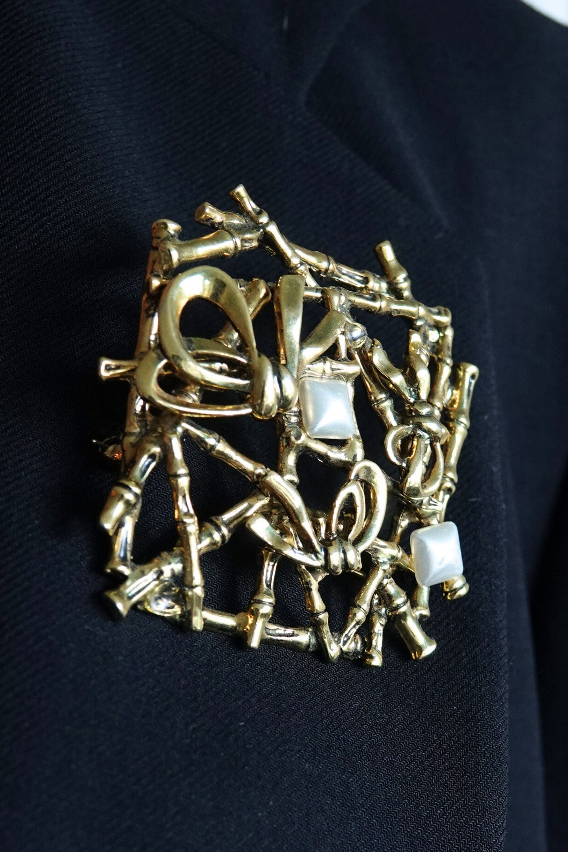 Gold bamboo lattice brooch — styled on black blazer lapel