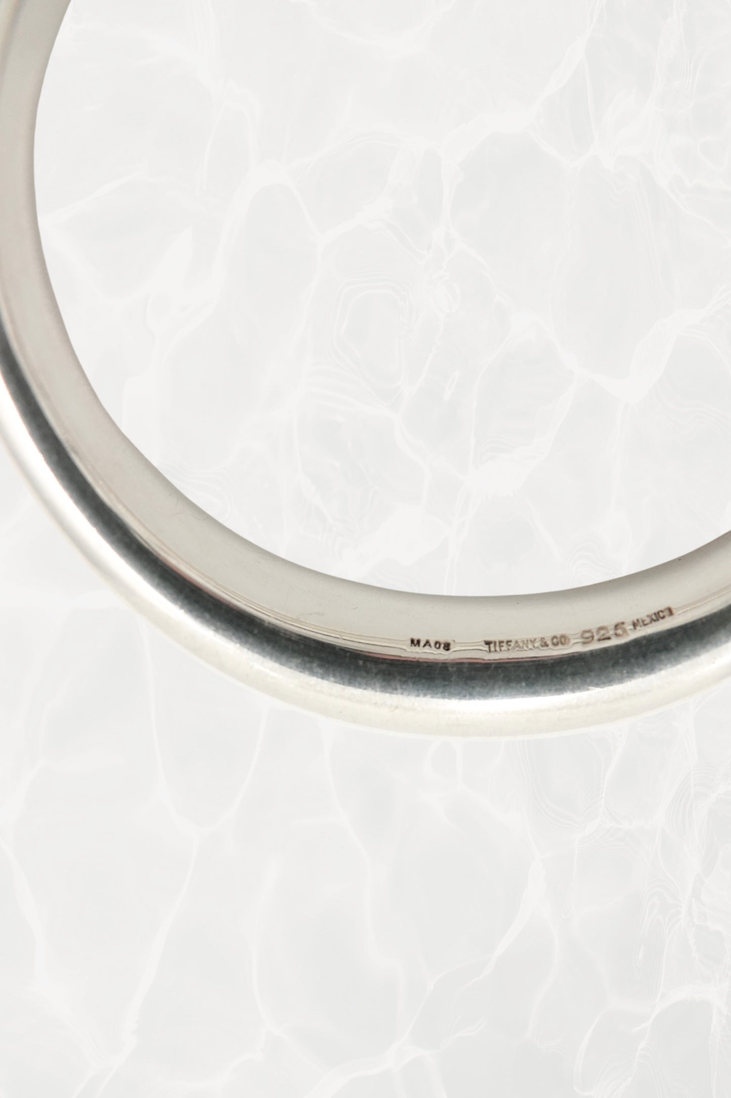 Elsa Peretti for Tiffany & Co. sculptural sterling silver closed bangle angled view: three-quarter angle showing the smooth sculptural volume and reflective polish of the organic closed form