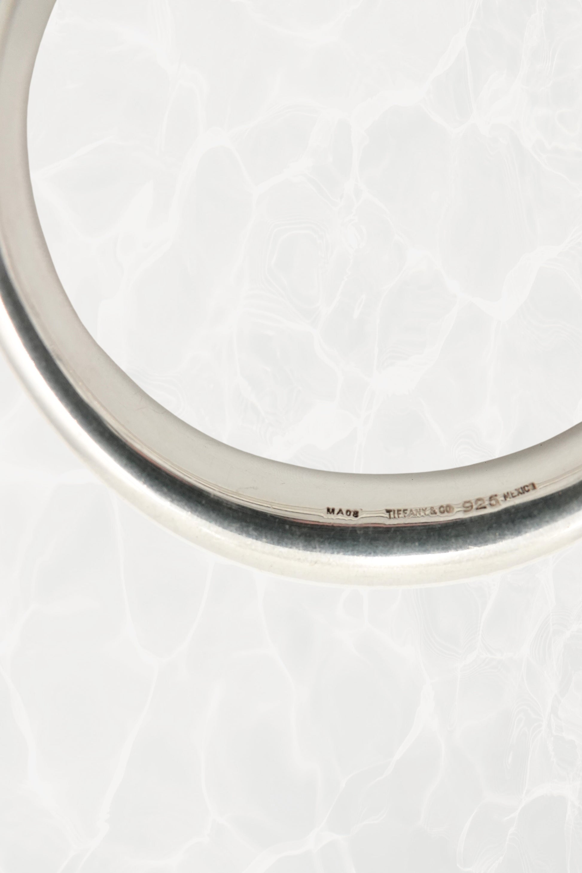 Elsa Peretti for Tiffany & Co. sculptural sterling silver closed bangle angled view: three-quarter angle showing the smooth sculptural volume and reflective polish of the organic closed form