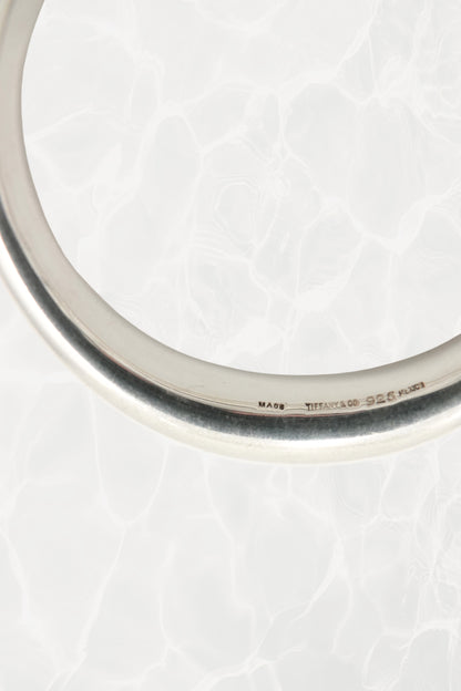 Elsa Peretti for Tiffany & Co. sculptural sterling silver closed bangle angled view: three-quarter angle showing the smooth sculptural volume and reflective polish of the organic closed form