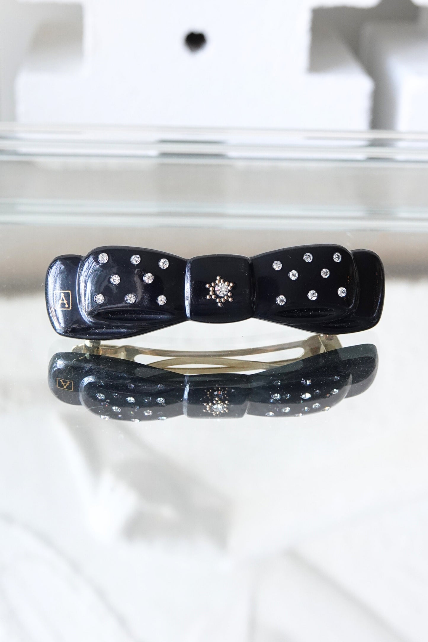 Alexandrine Paris rhinestone bow barrette, A logo visible — styled on reflective surface — Disco Palma