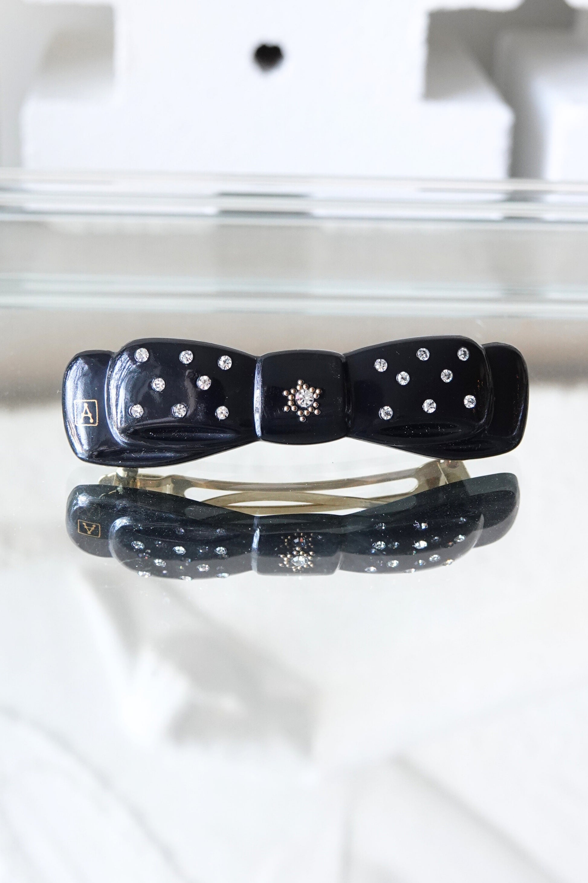 Alexandrine Paris rhinestone bow barrette, A logo visible — styled on reflective surface — Disco Palma