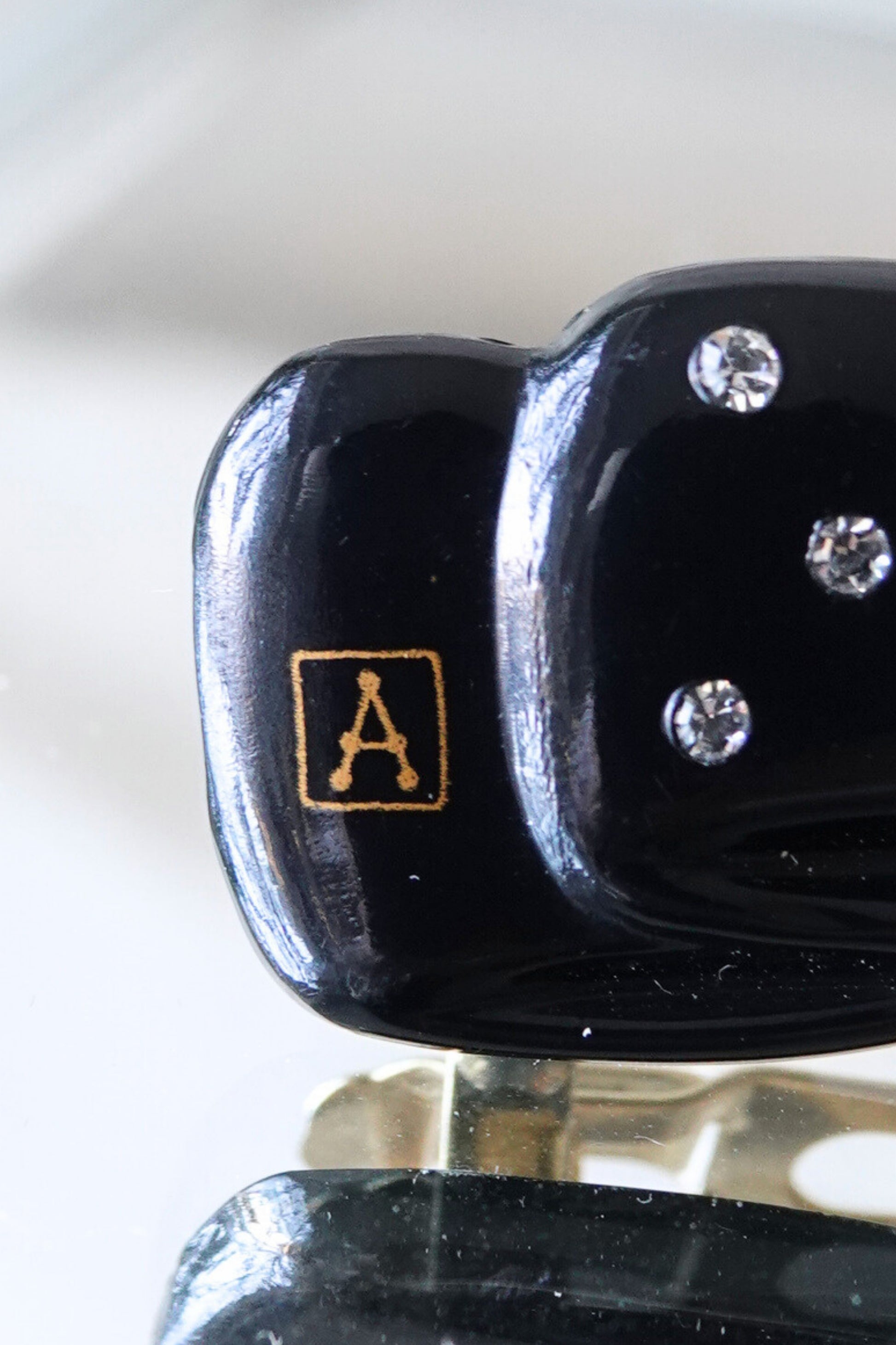 Alexandrine Paris A logo close-up — gold cartouche on black lacquer