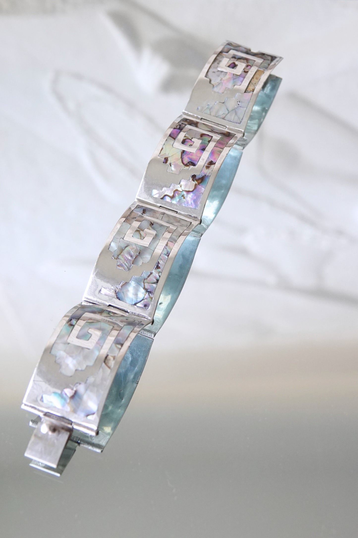 Mexican 925 silver abalone mosaic cuff bracelet flat on glass surface
