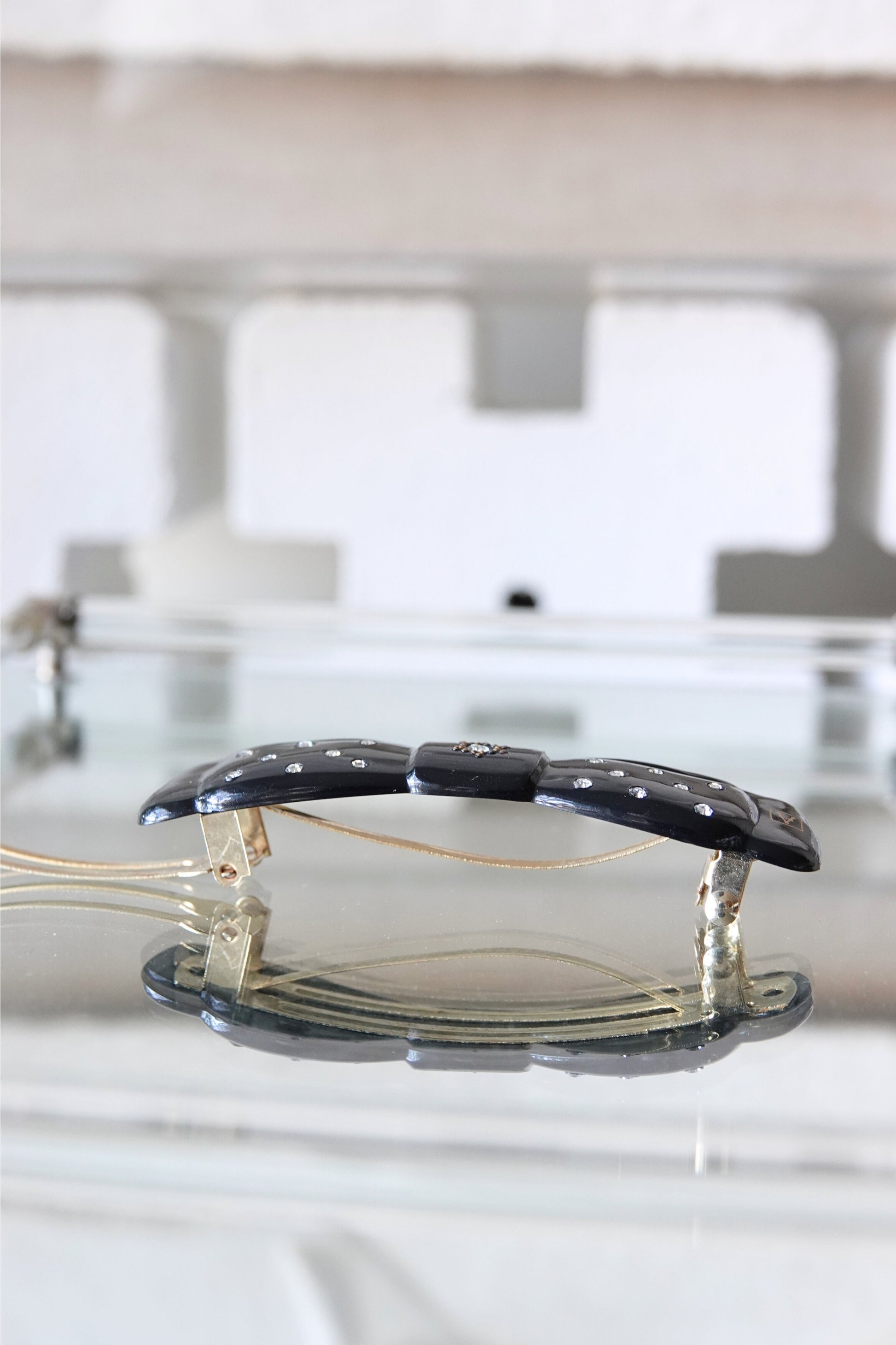 Black lacquer rhinestone barrette — angled view showing full bow shape