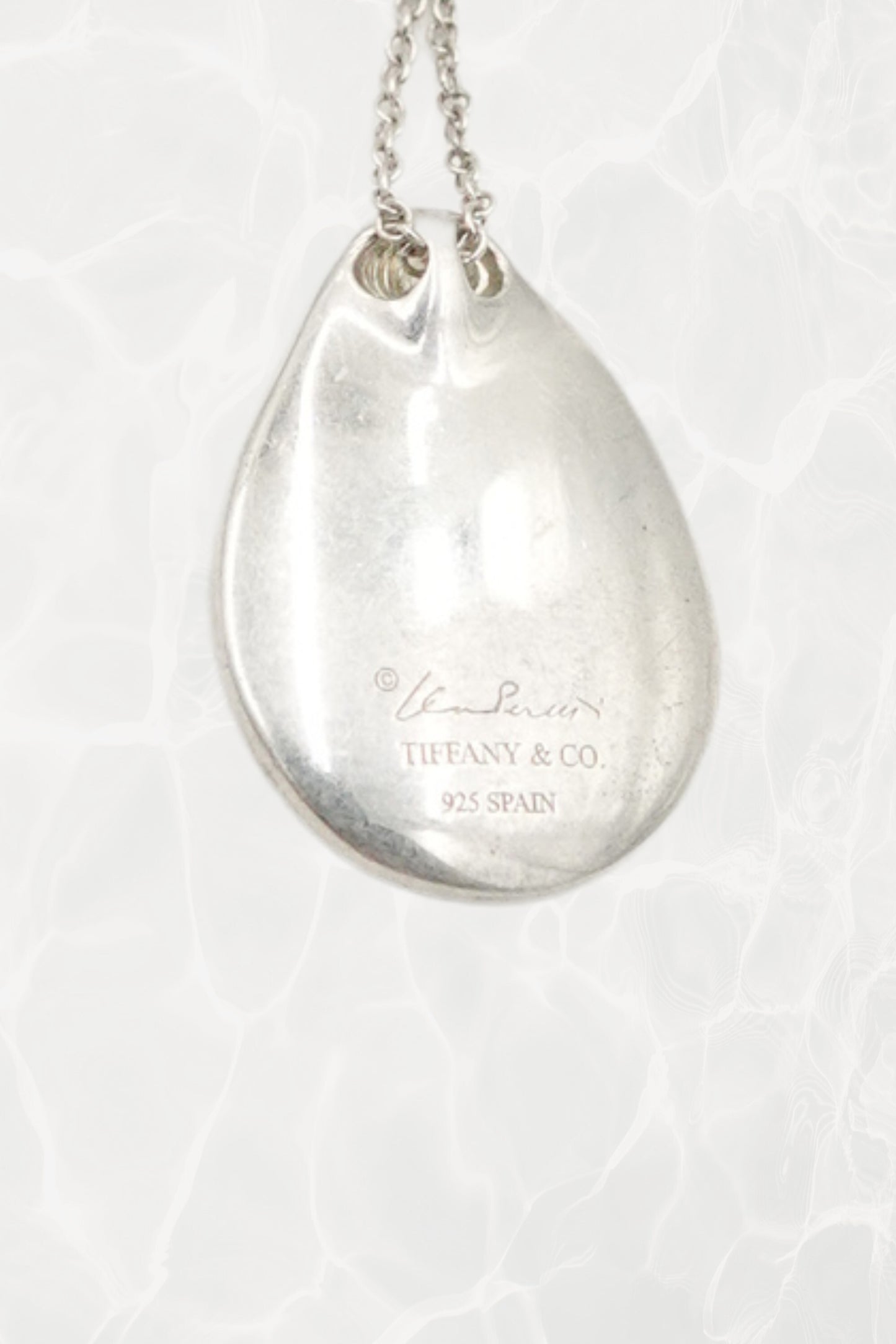 Elsa Peretti for Tiffany & Co. sterling silver Madonna pendant necklace: overhead flat lay view showing full chain and pendant together on neutral surface