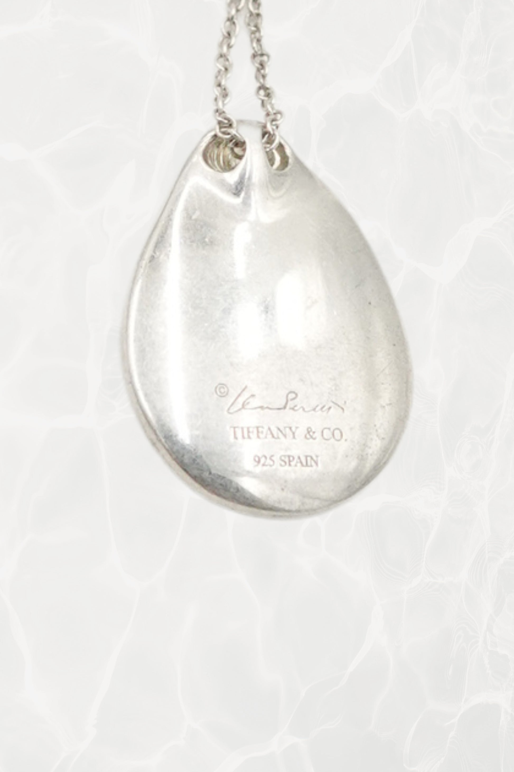 Elsa Peretti for Tiffany & Co. sterling silver Madonna pendant necklace: overhead flat lay view showing full chain and pendant together on neutral surface