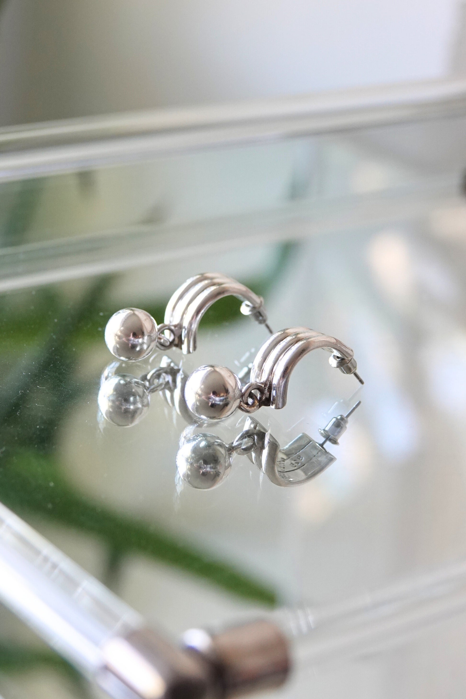 Sterling silver crescent earrings — styled on glass surface