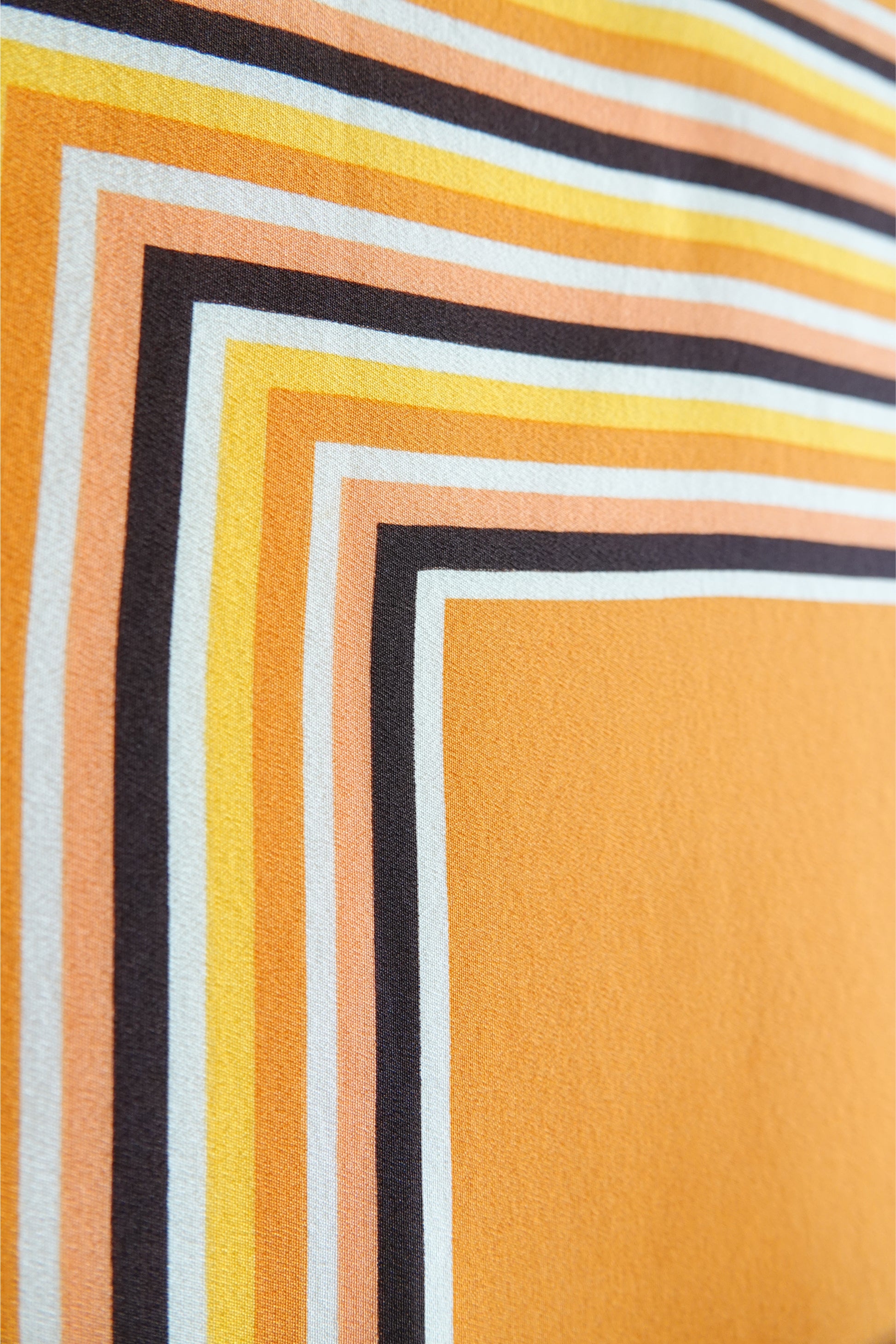 1970s YSL Yves Saint Laurent silk scarf: draped view showing the fluidity and drape of the silk fabric with the concentric square stripe print in brown and orange