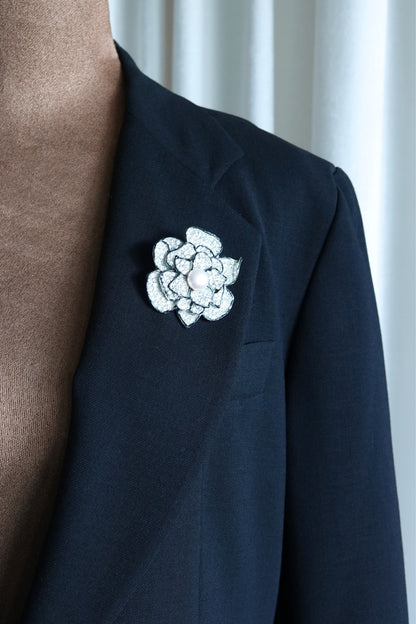 Rhinestone camellia brooch — three-quarter view on glass surface