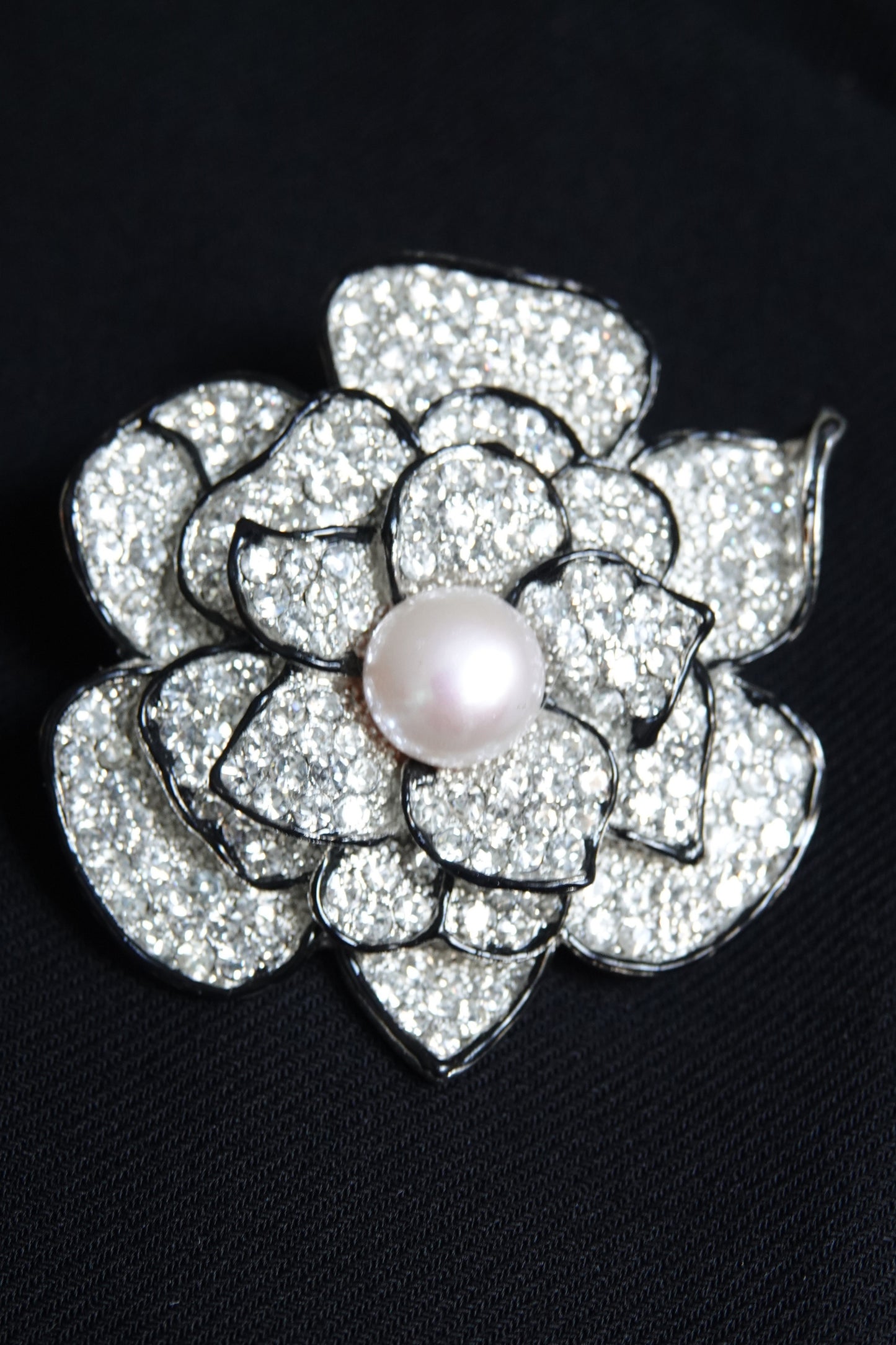 Pavé rhinestone flower brooch with pearl center — styled on dark background