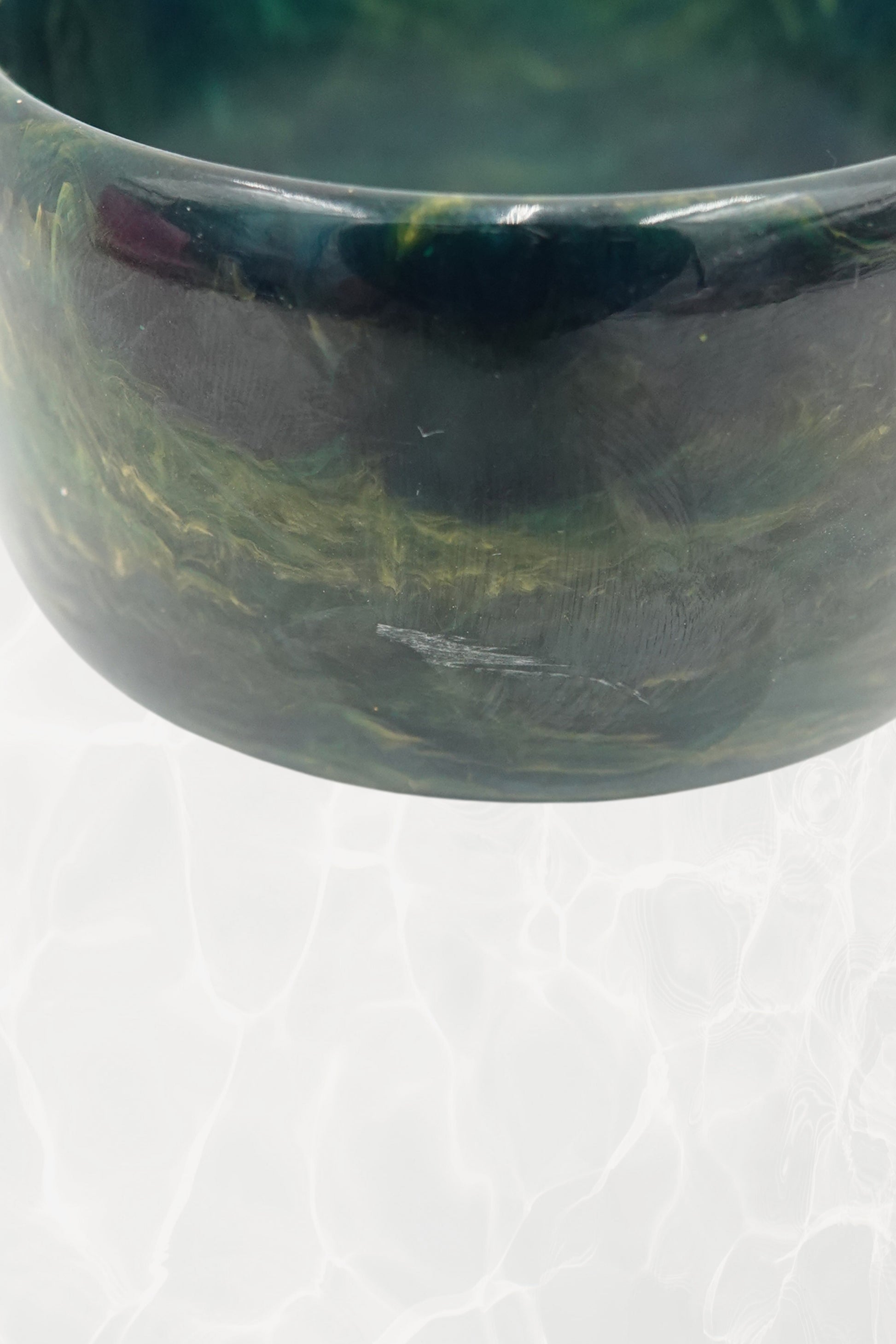 Close-up of deep green marbled bangle showing teal and amber swirls