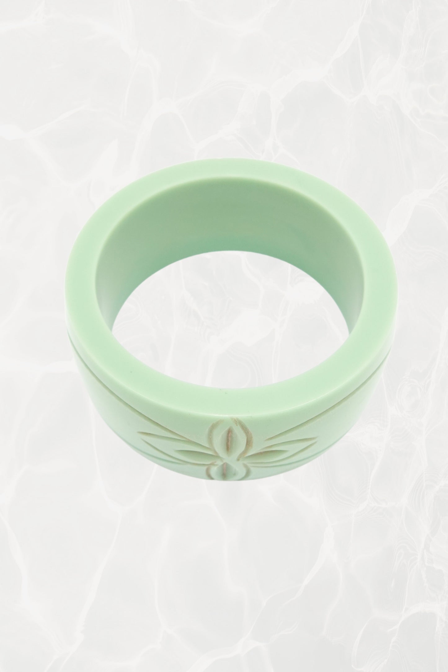 Carved Bakelite bangle — angled view showing floral relief detail