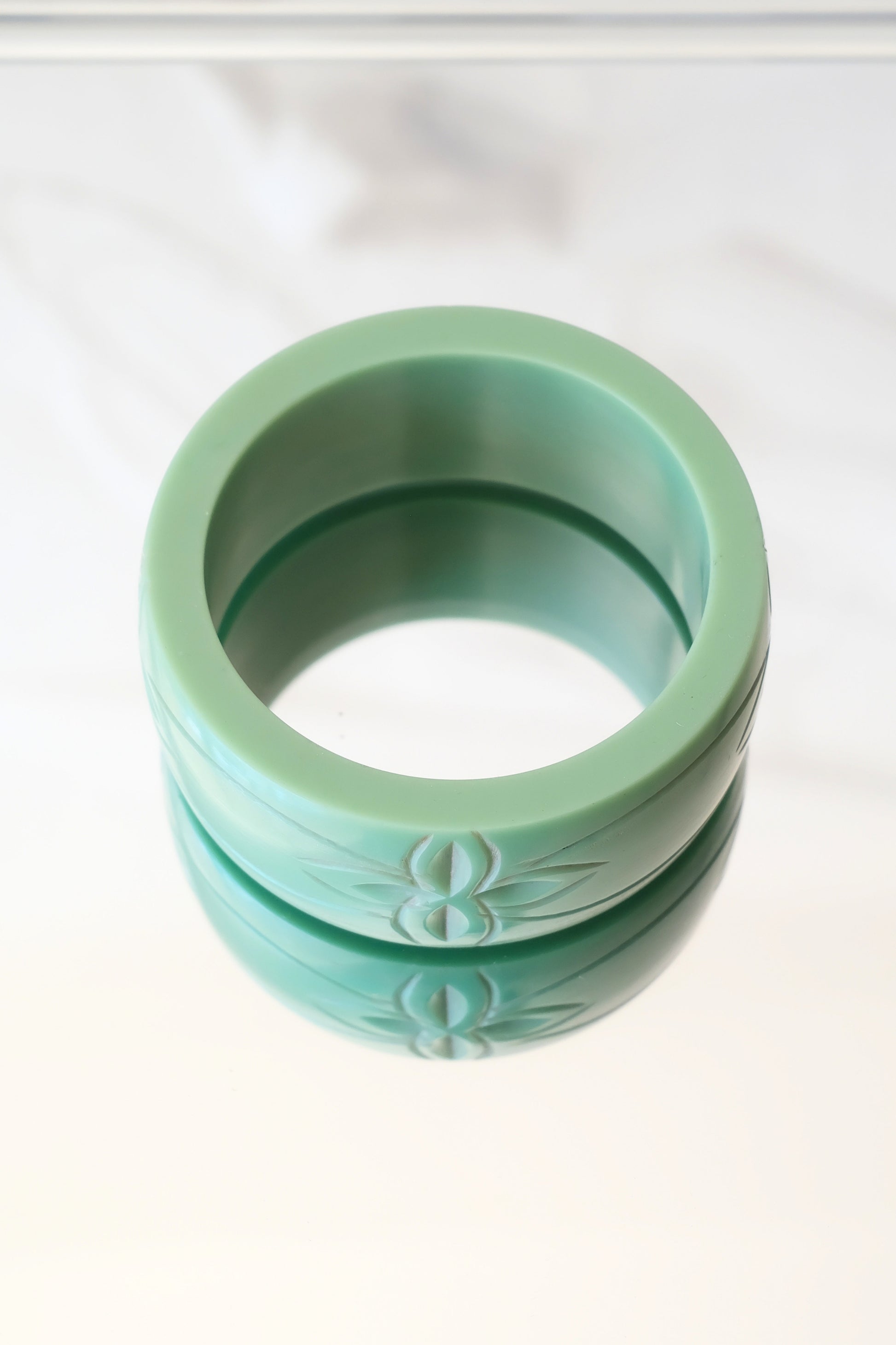 Vintage Bakelite bangle, carved botanical motif — styled stacked view on reflective surface — Disco Palma