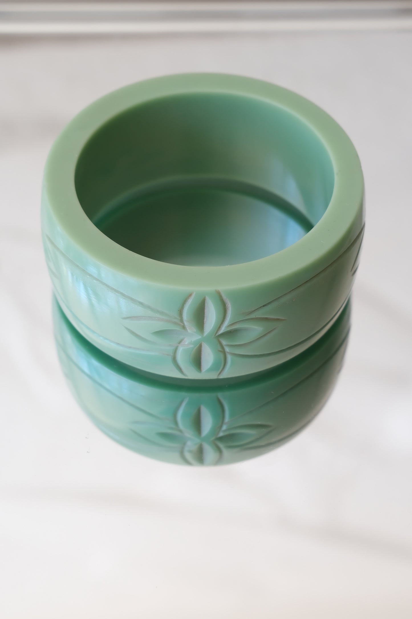 Vintage Bakelite bangle, carved botanical motif front view — styled on reflective marble — Disco Palma