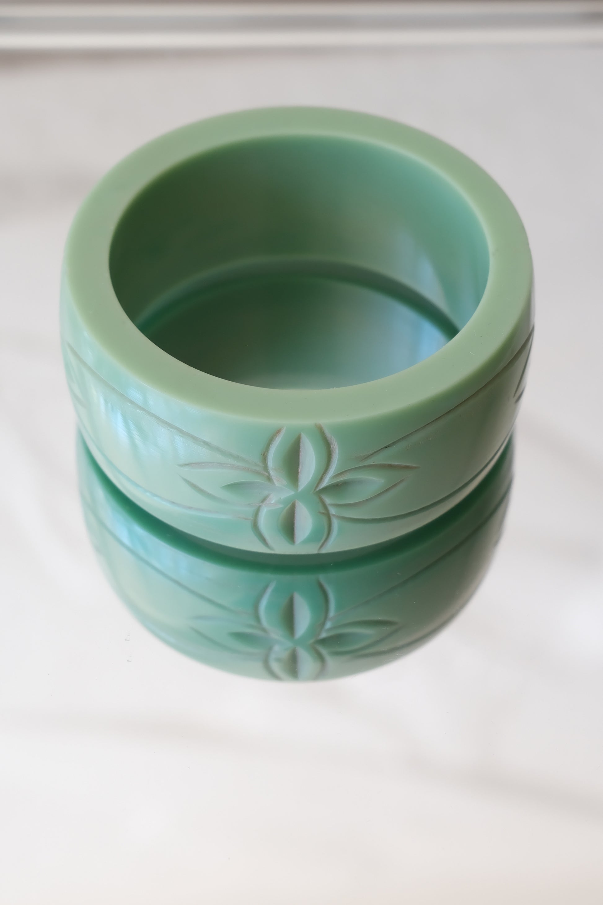 Vintage Bakelite bangle, carved botanical motif front view — styled on reflective marble — Disco Palma