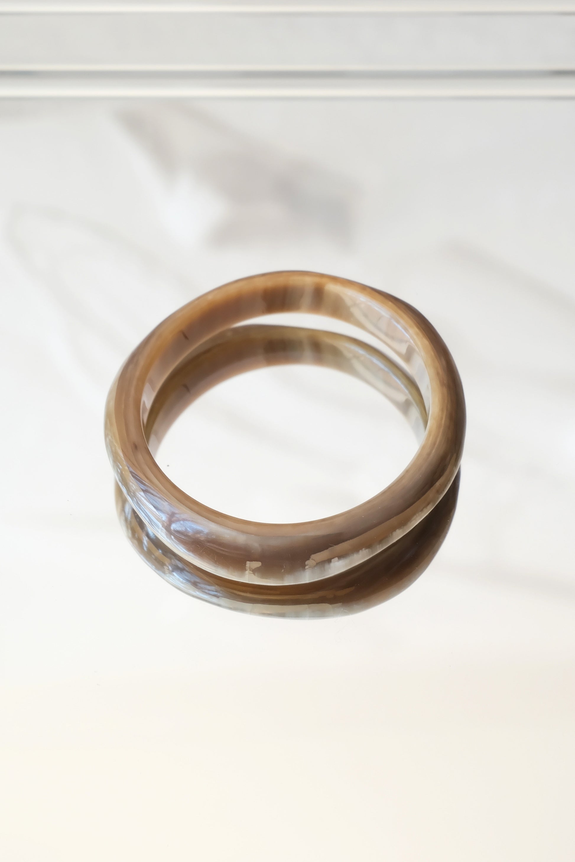 Natural horn bangle — styled overhead on marble surface with shadow detail